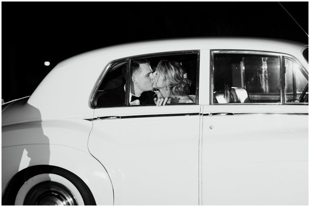 newlyweds kiss in the backseat of vintage car as they drive away