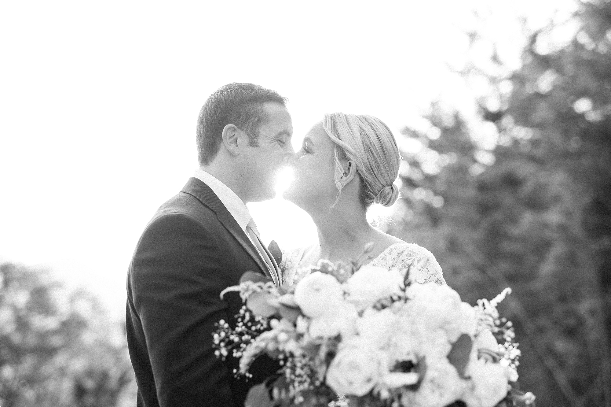 bride and groom kiss with sunlight streaming around them