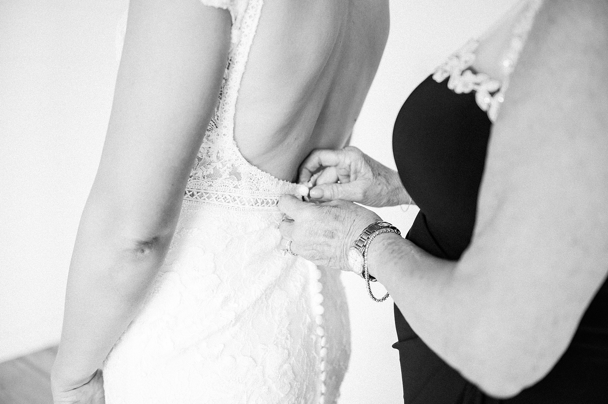 mother of the bride helping bride into dress