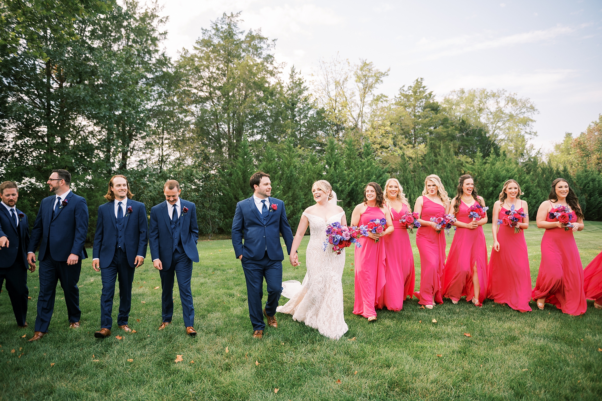 couple walk together with bridal party