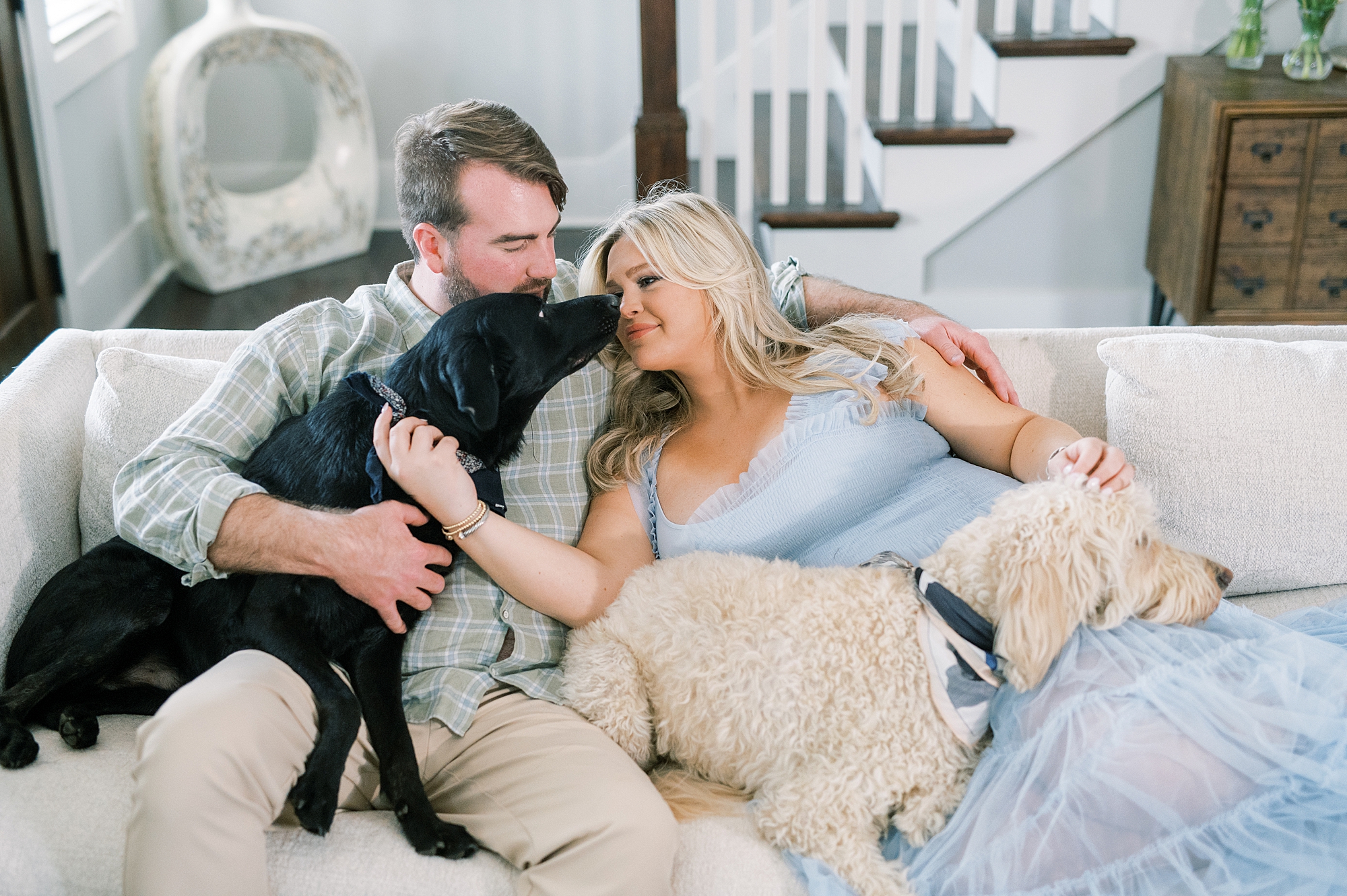 couple snuggle with dogs on couch during engagement