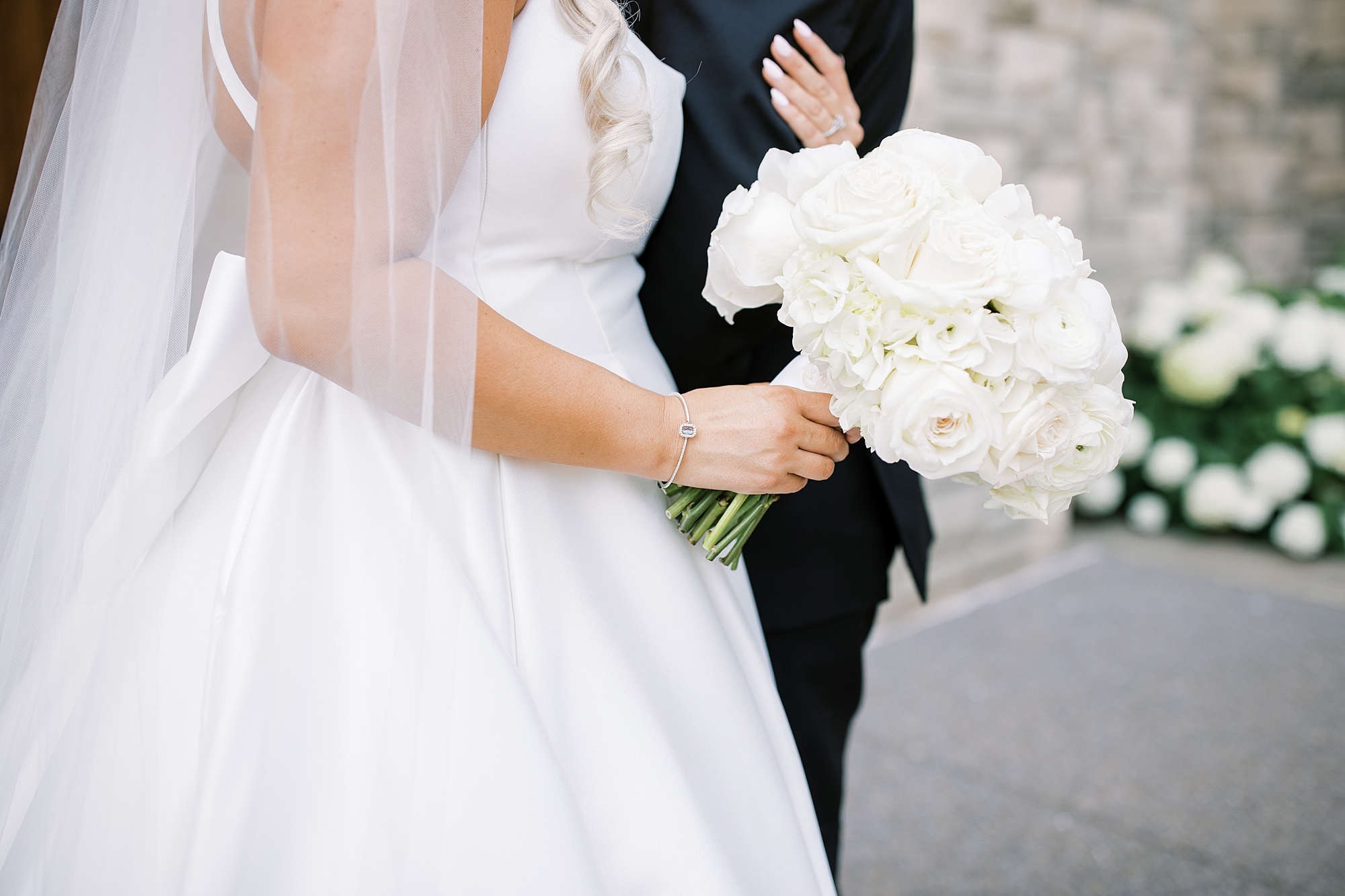 bride holding long-stemmed white rose bouquet