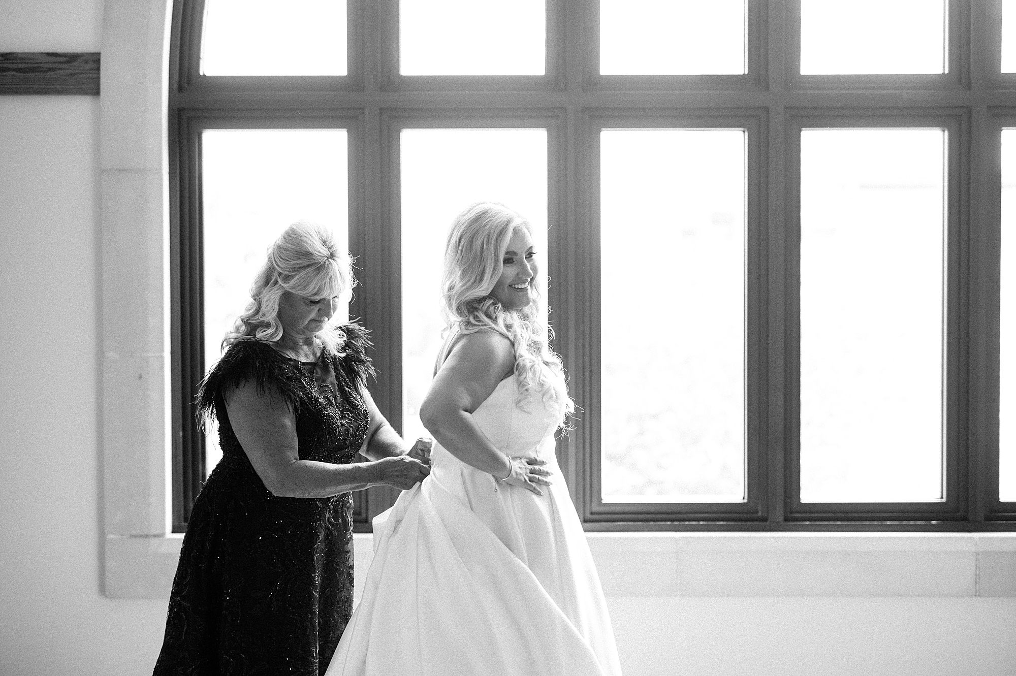 mother of the bride helping daughter into dress