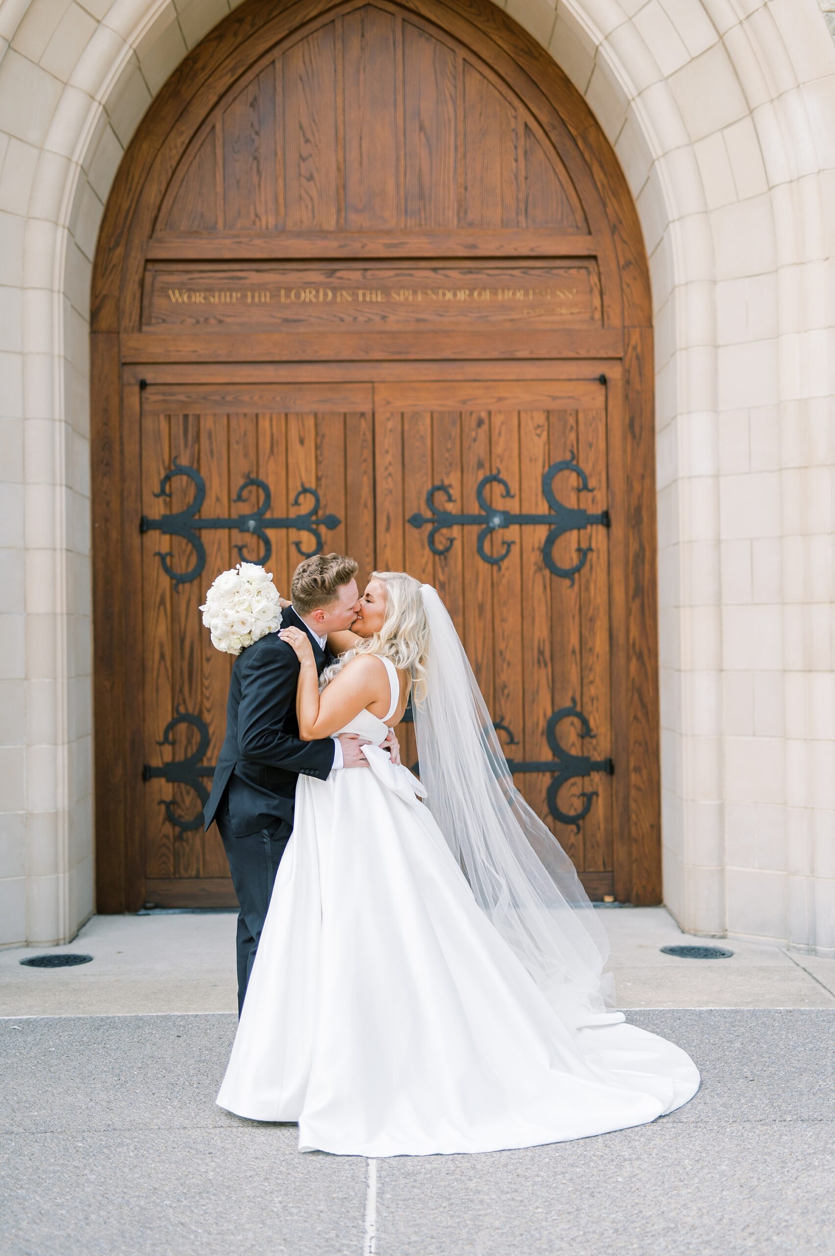 bride and groom kiss in front of church