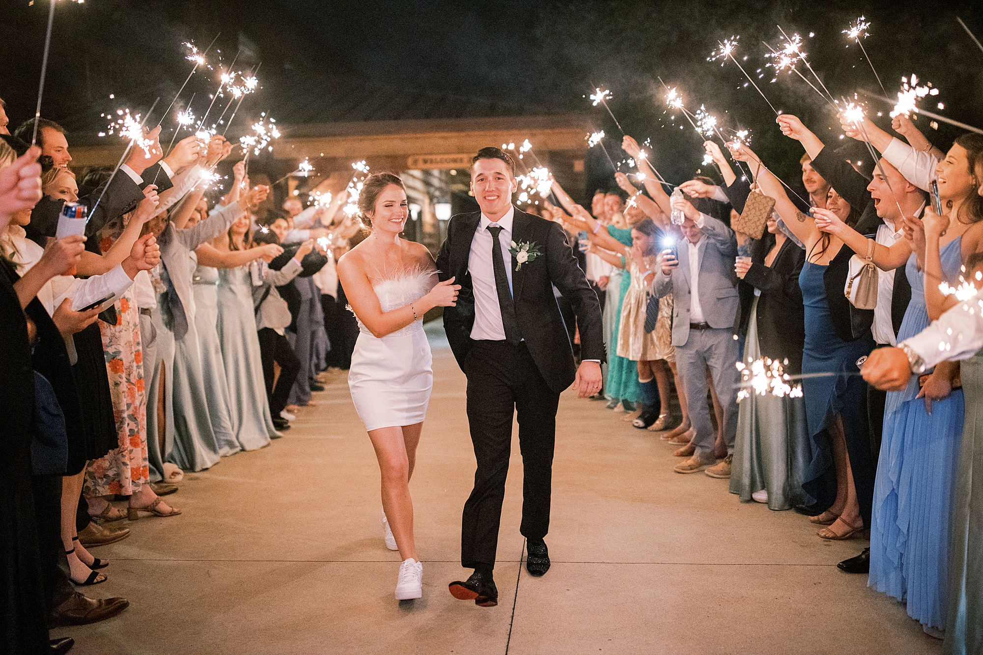 newlyweds exit wedding reception while guests hold sparklers