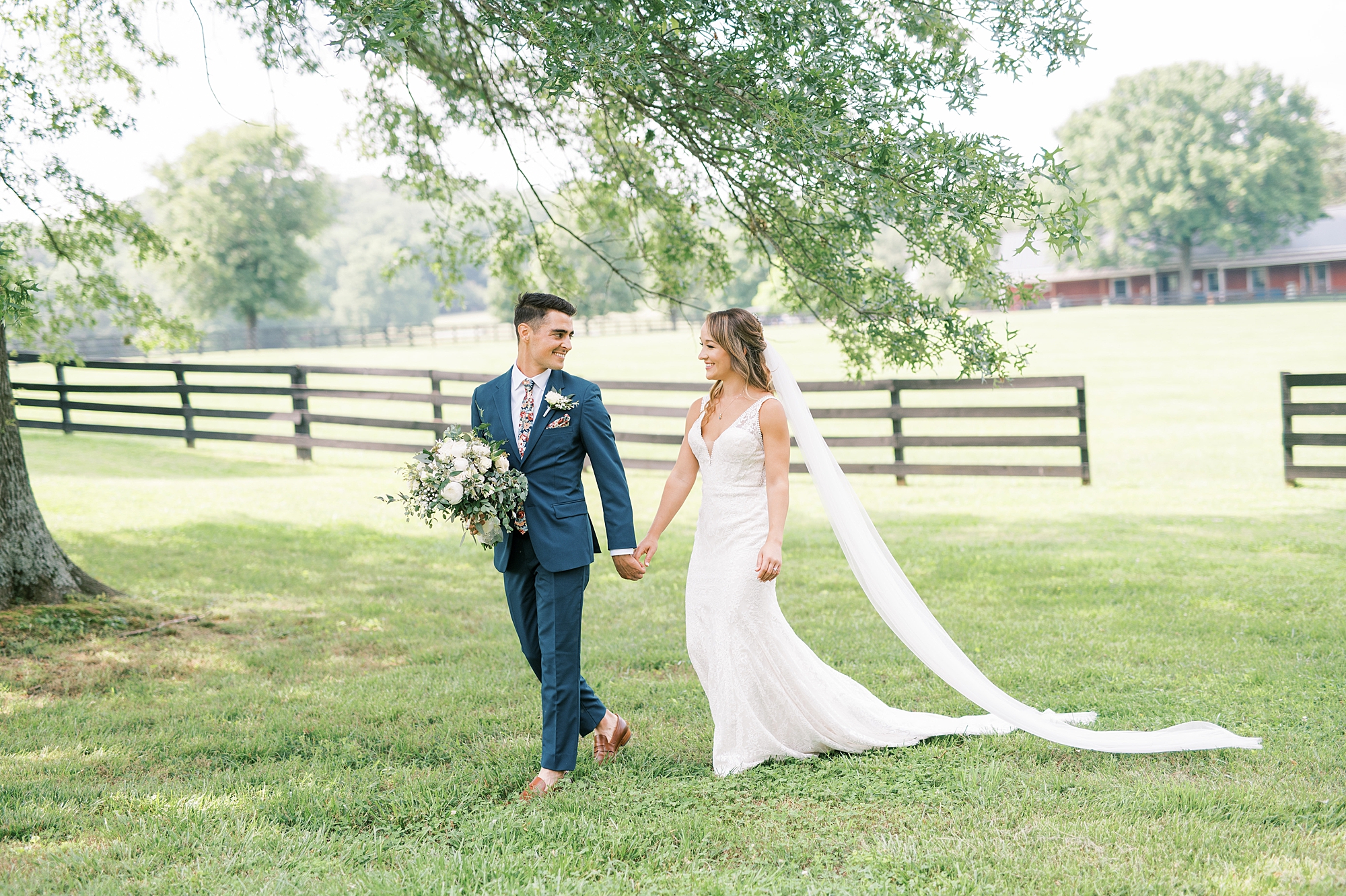 bride and groom hold hands as they walk across the grounds of Cedarmont Farm 