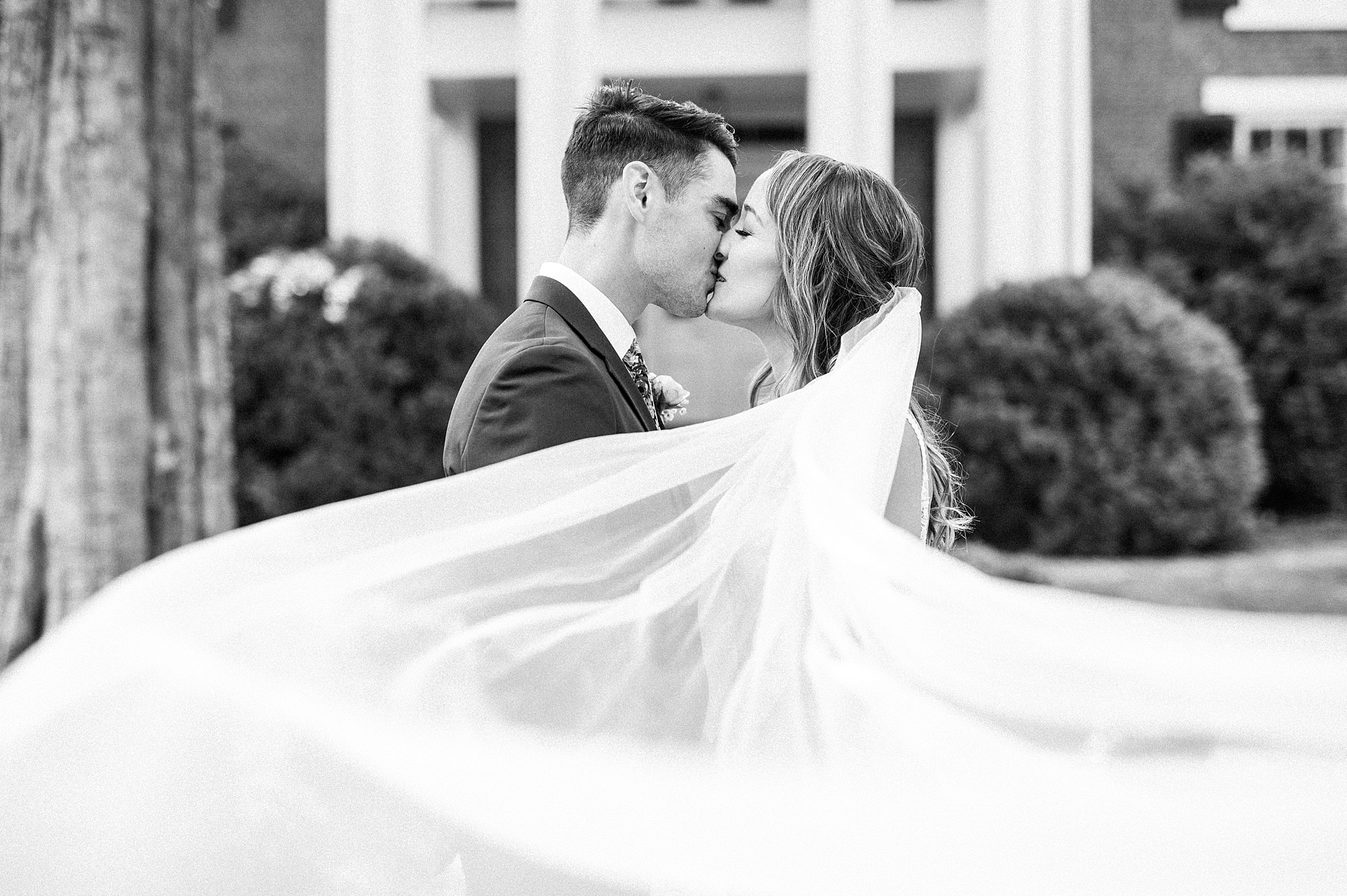 newlyweds kiss as veil floats around them