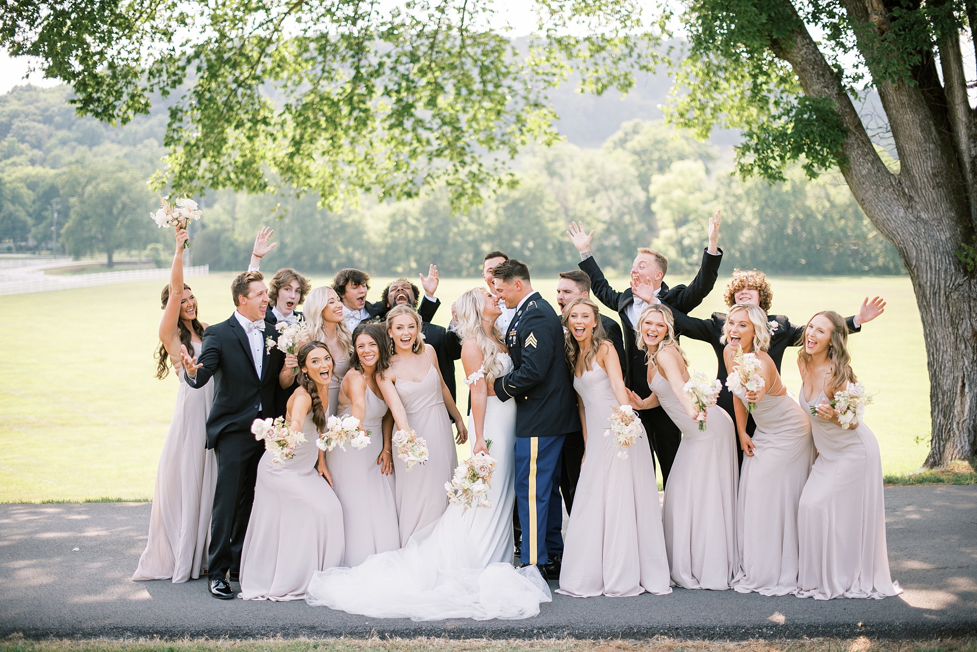 wedding party cheers as bride and groom kiss 