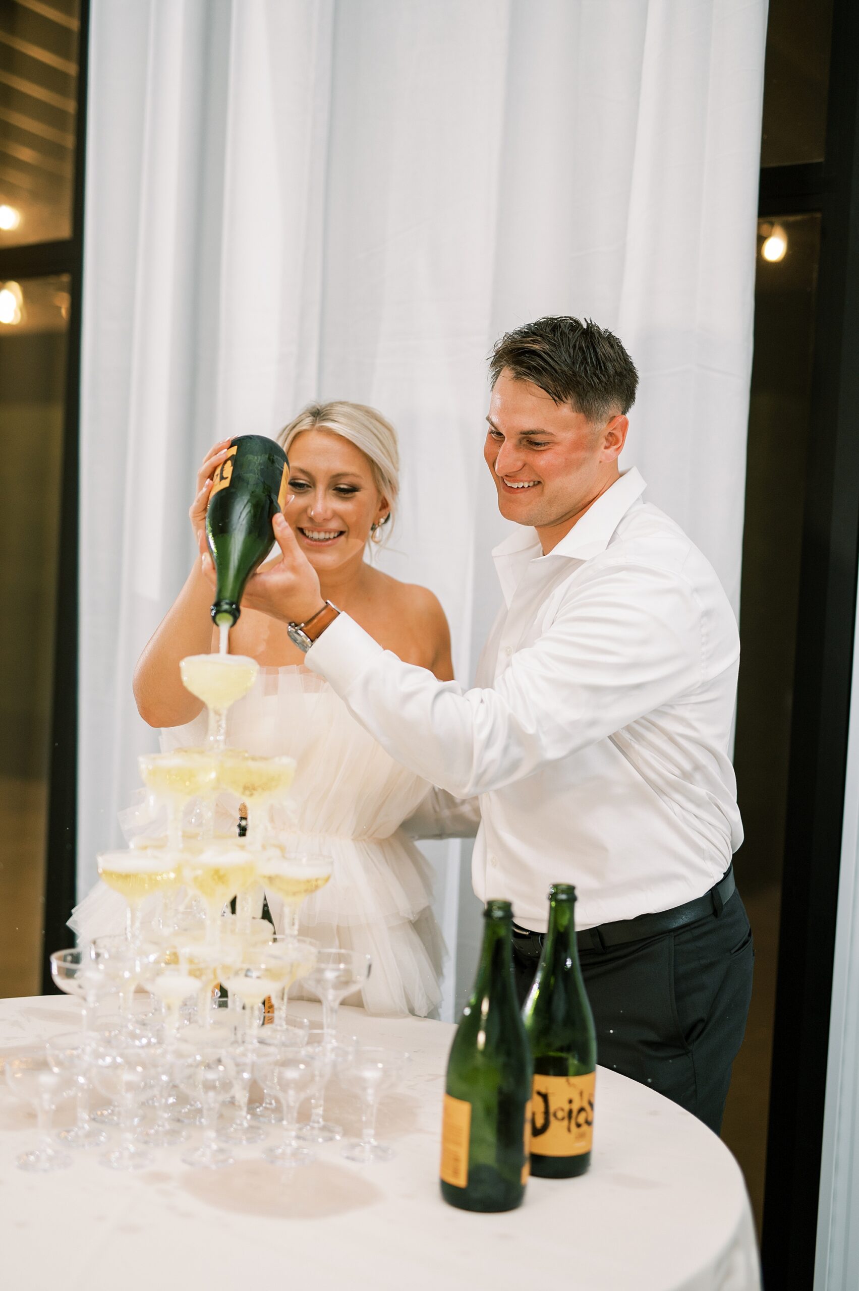 newlyweds pour champagne over tower of glasses