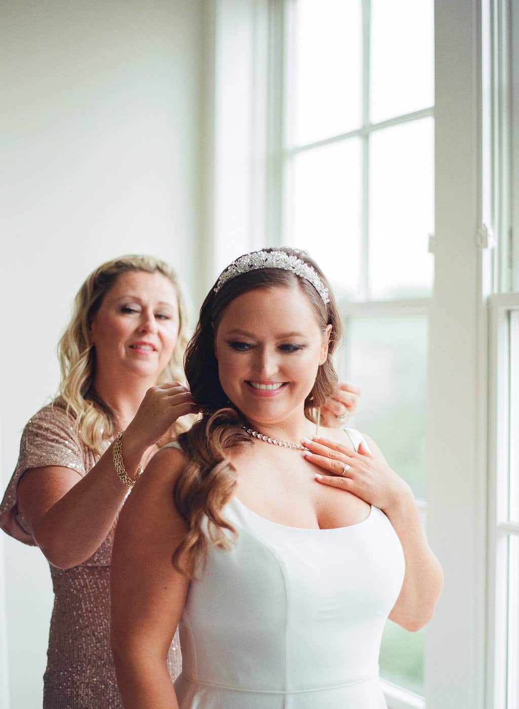 mom helps bride with necklace