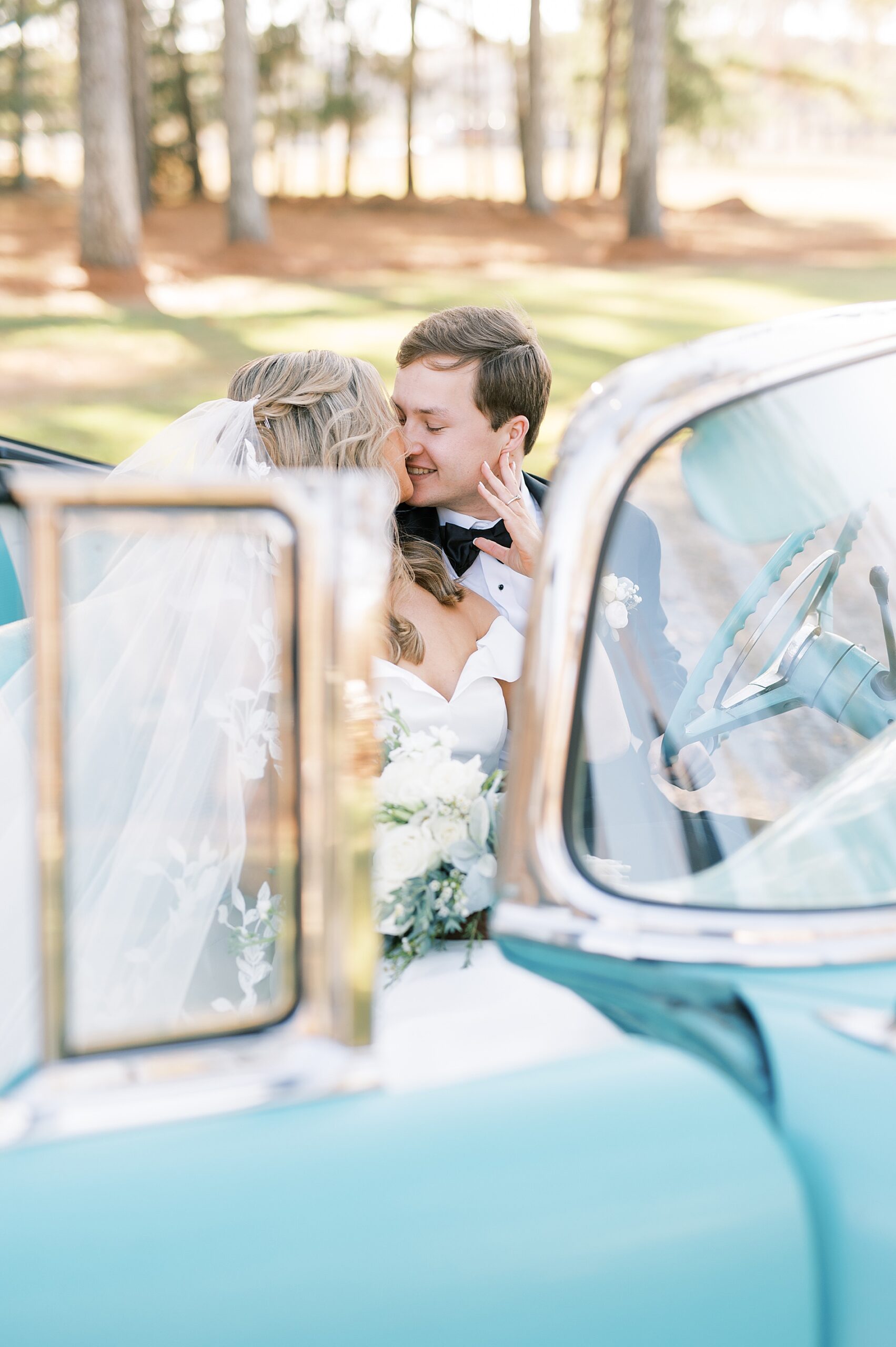 bride and groom sit in classic car