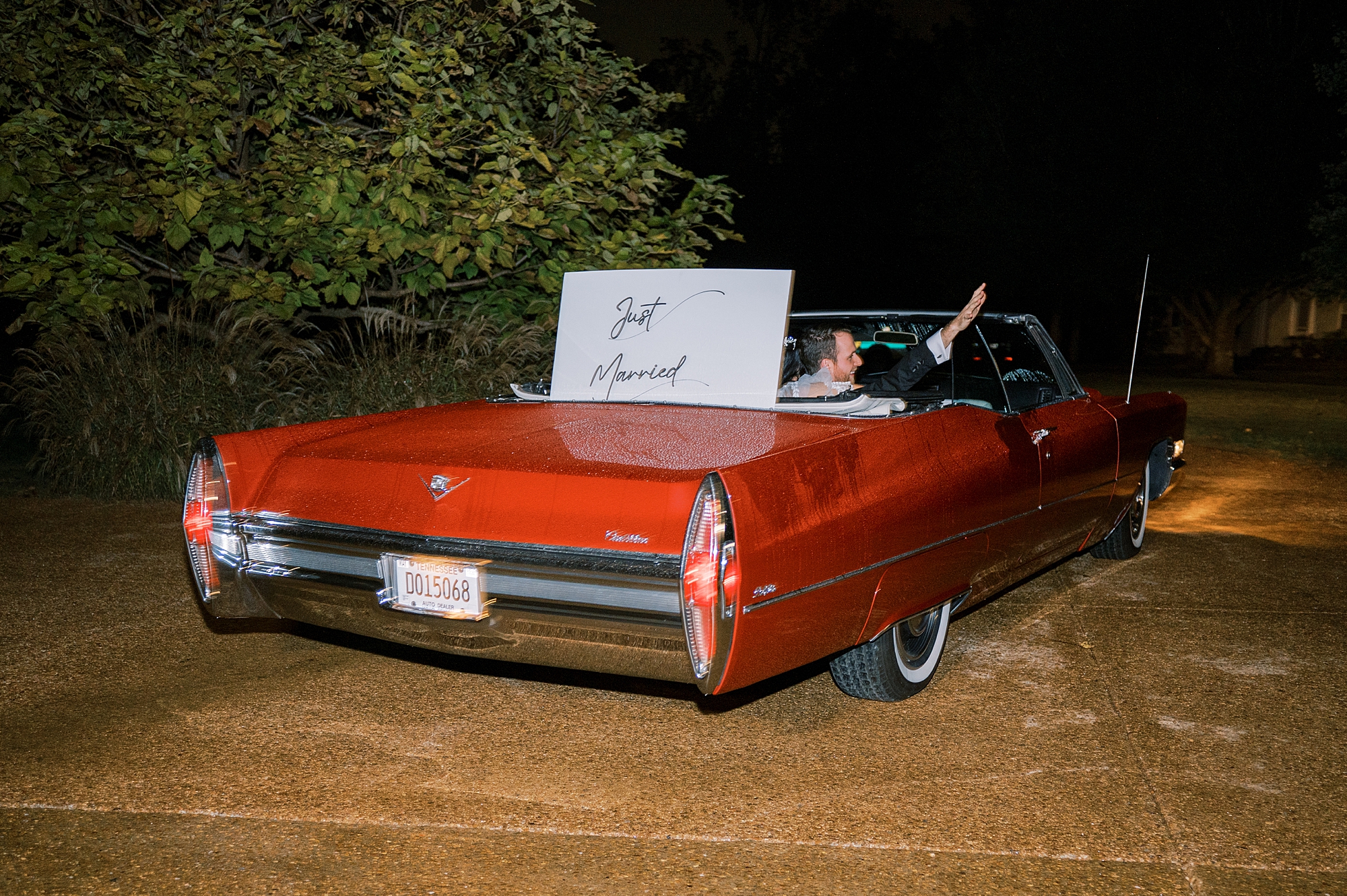 newlyweds exit wedding in red convertible with just married sign 