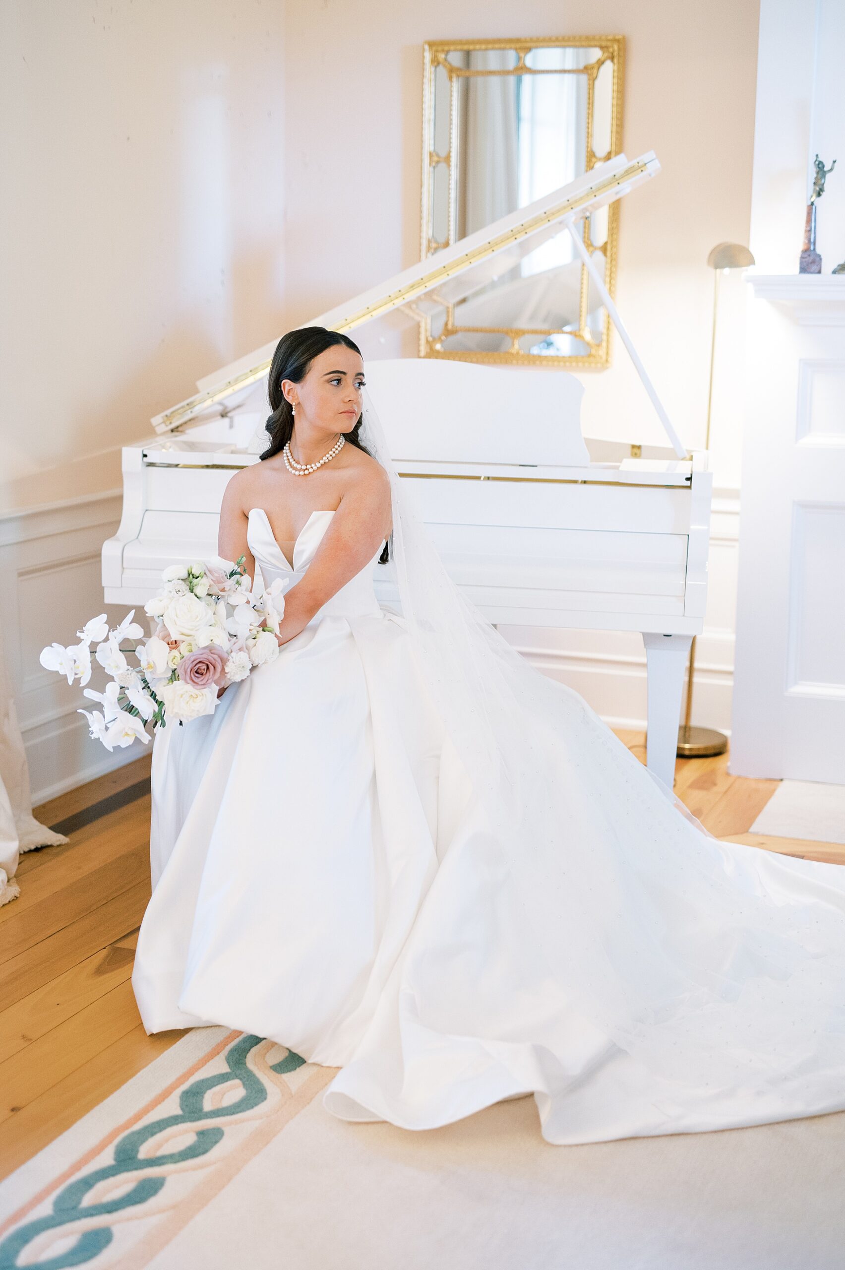 bride in gown sitting on bench of grand piano 