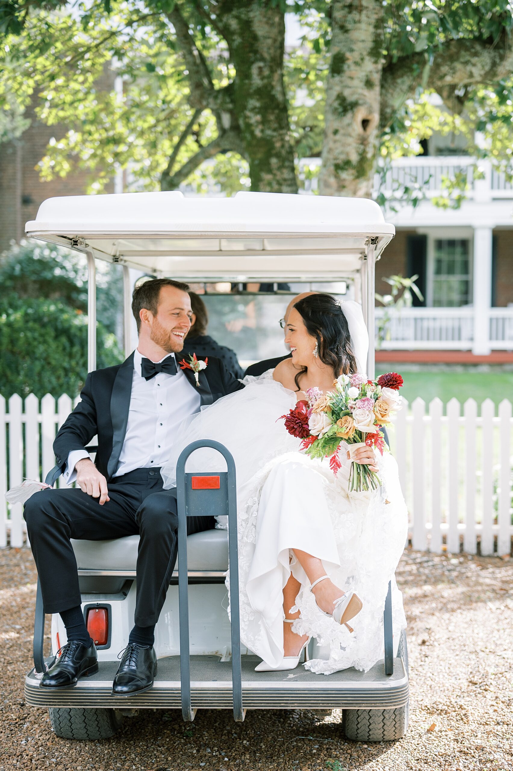 bride and groom sit on back of golf cart