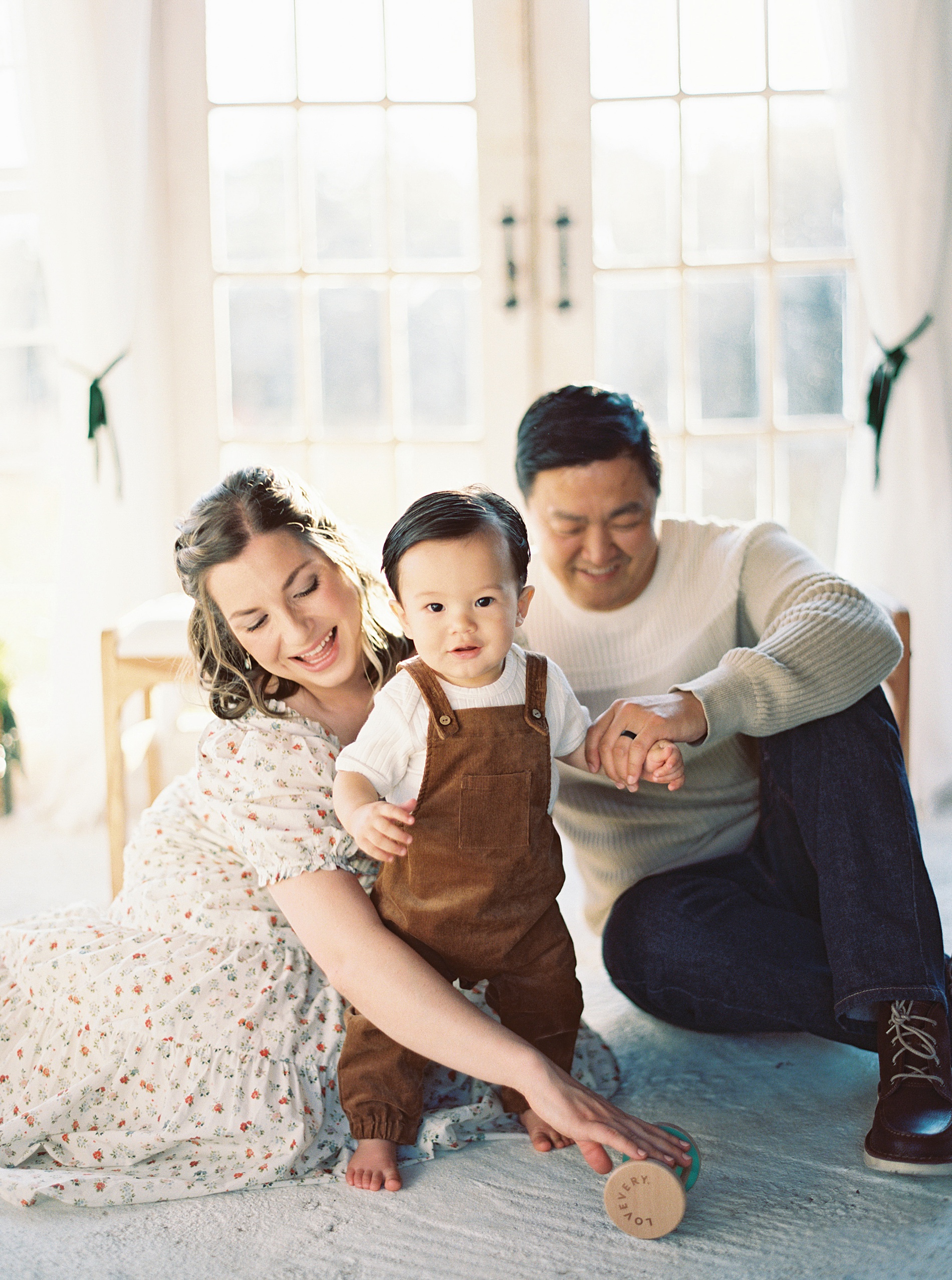 family of three plays on floor