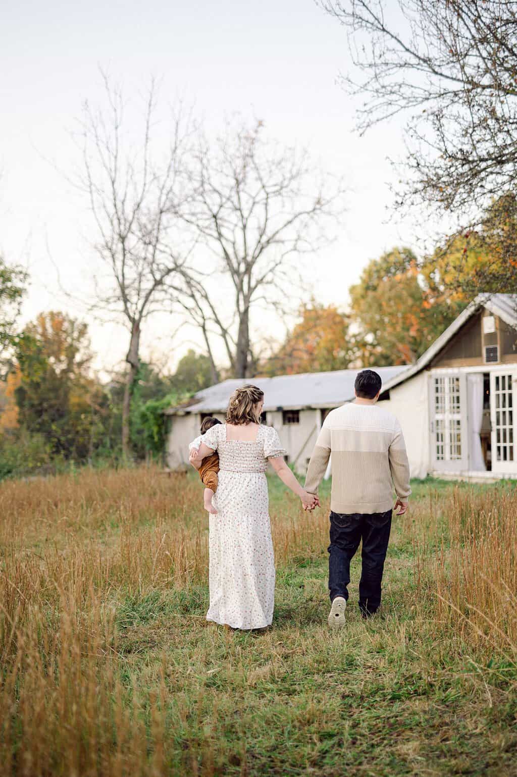 mom holds son and walks back towards house holding hands with husband
