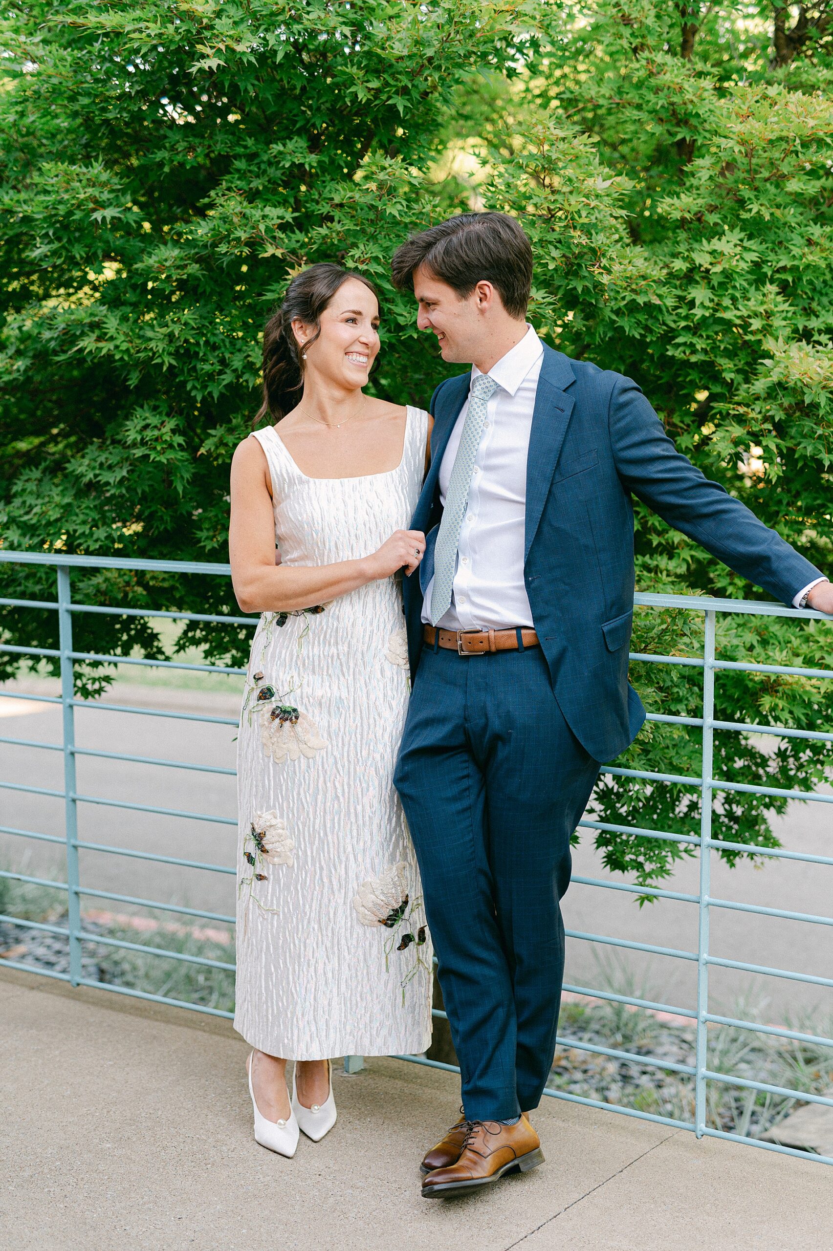 future bride and groom lean against railing for portraits at rehearsal dinner 