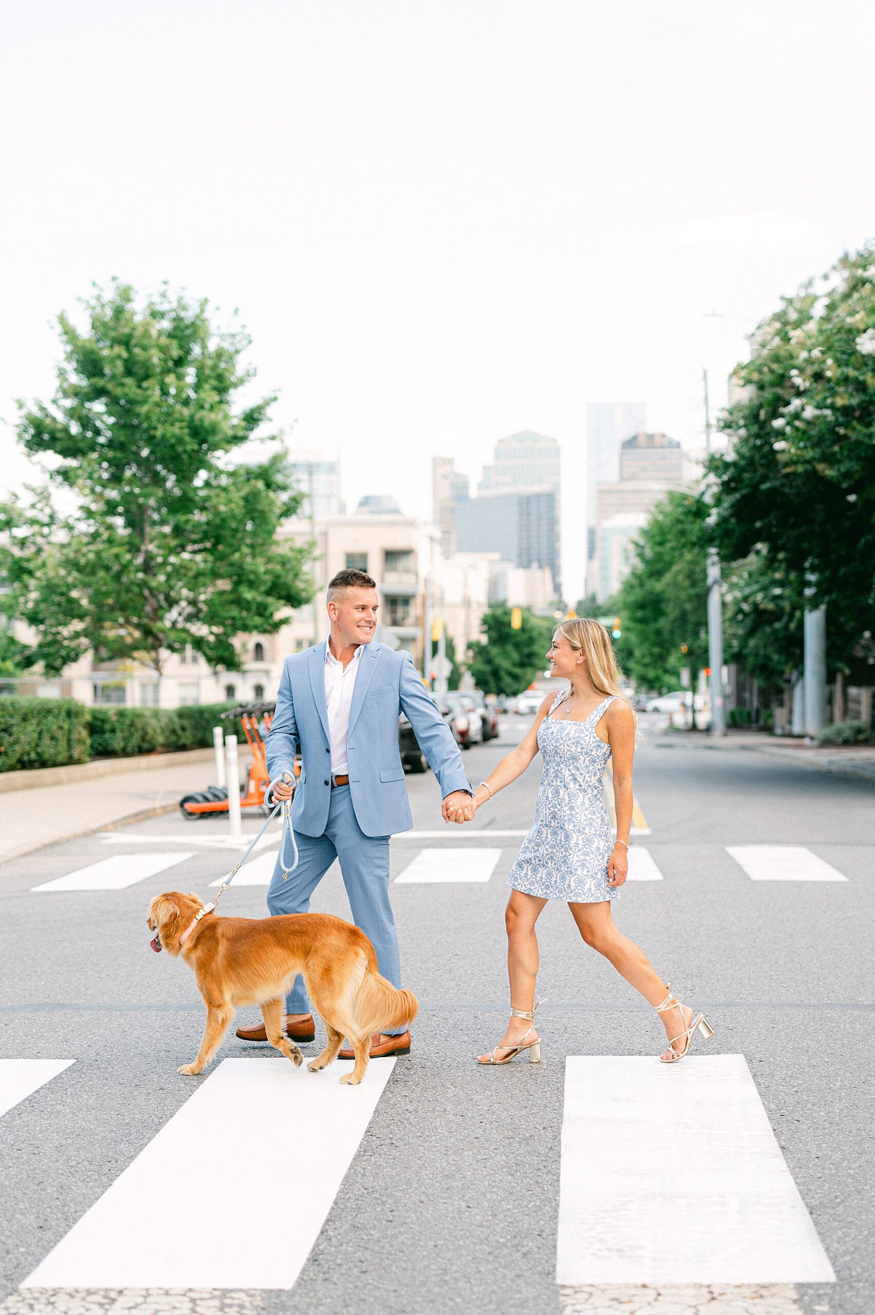 couple walk across street with their dog during summer engagement session