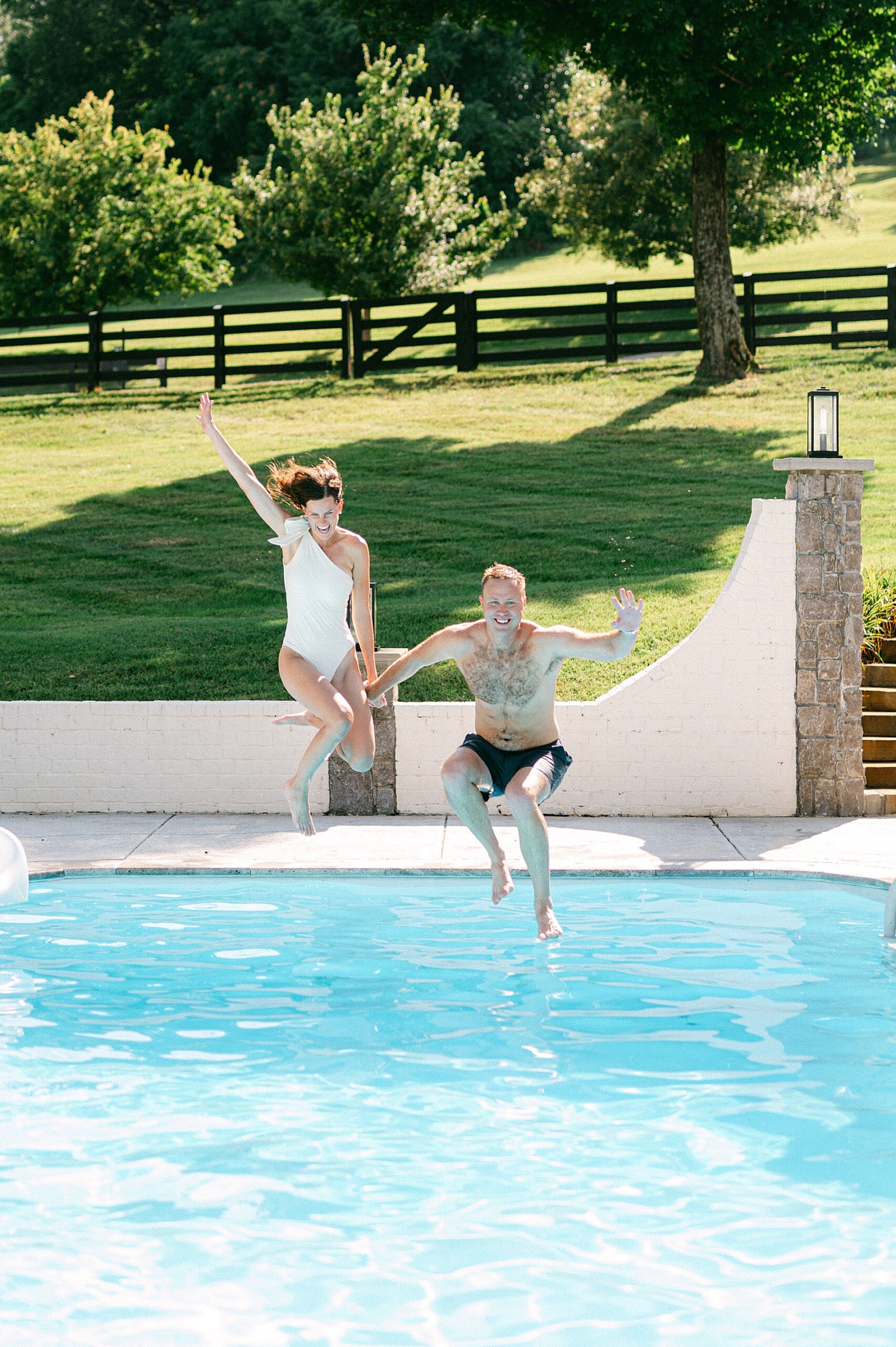 candid engagement photography of couple jumping into pool