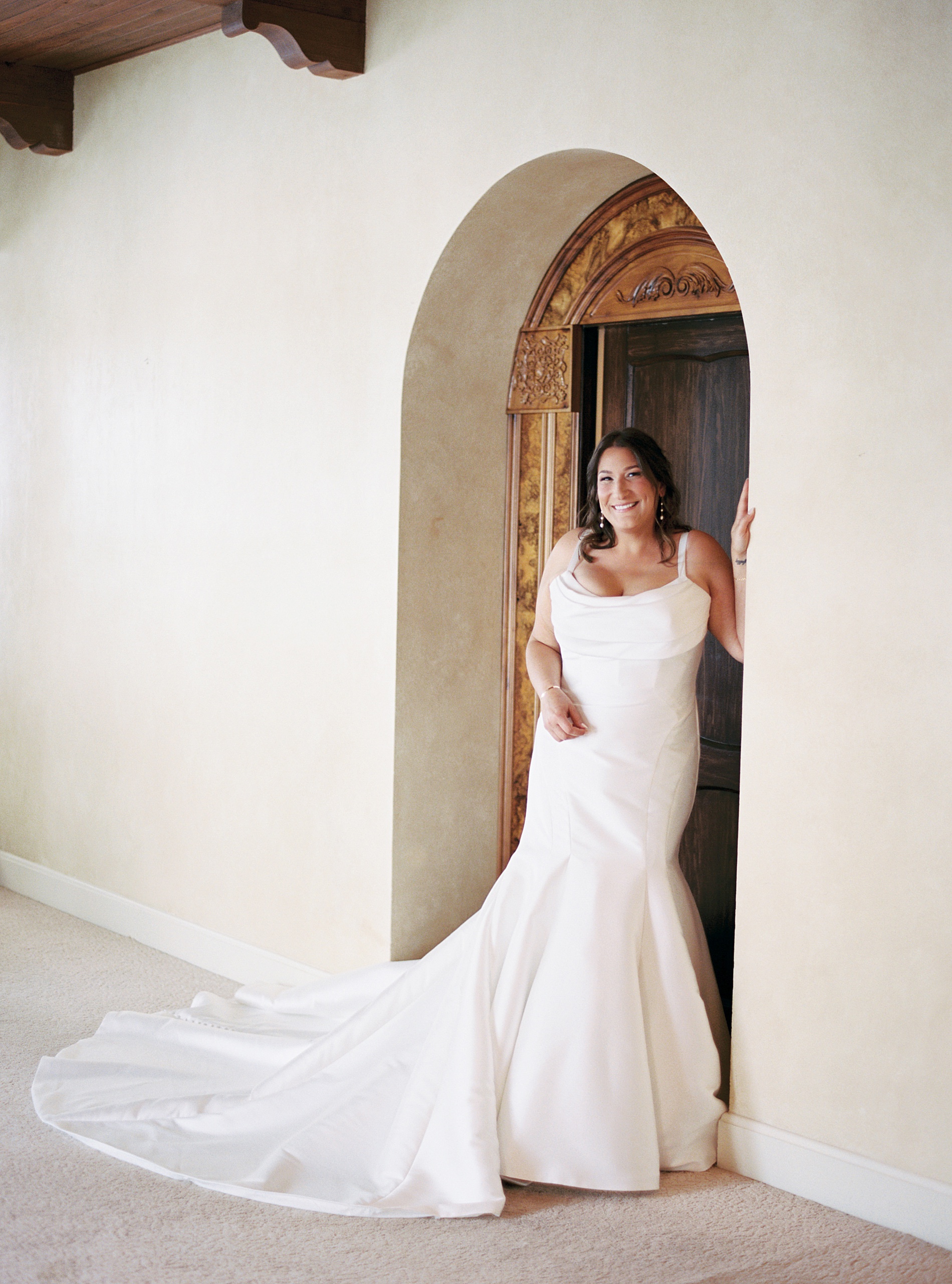 bride in wedding dress stands in arched entryway