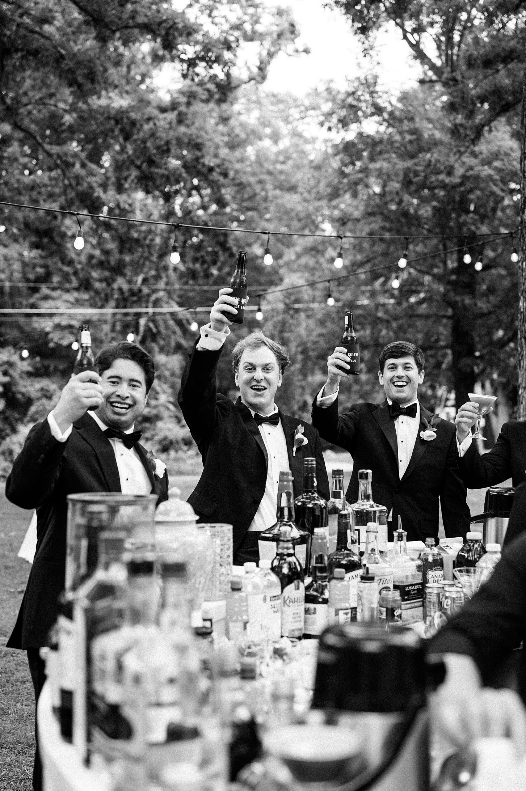 groomsmen hold up a drink in their hand during cocktail hour