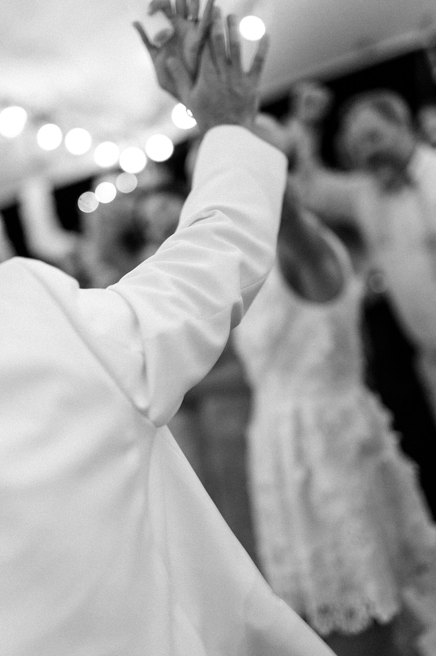 bride and groom hold hands up in the air at reception